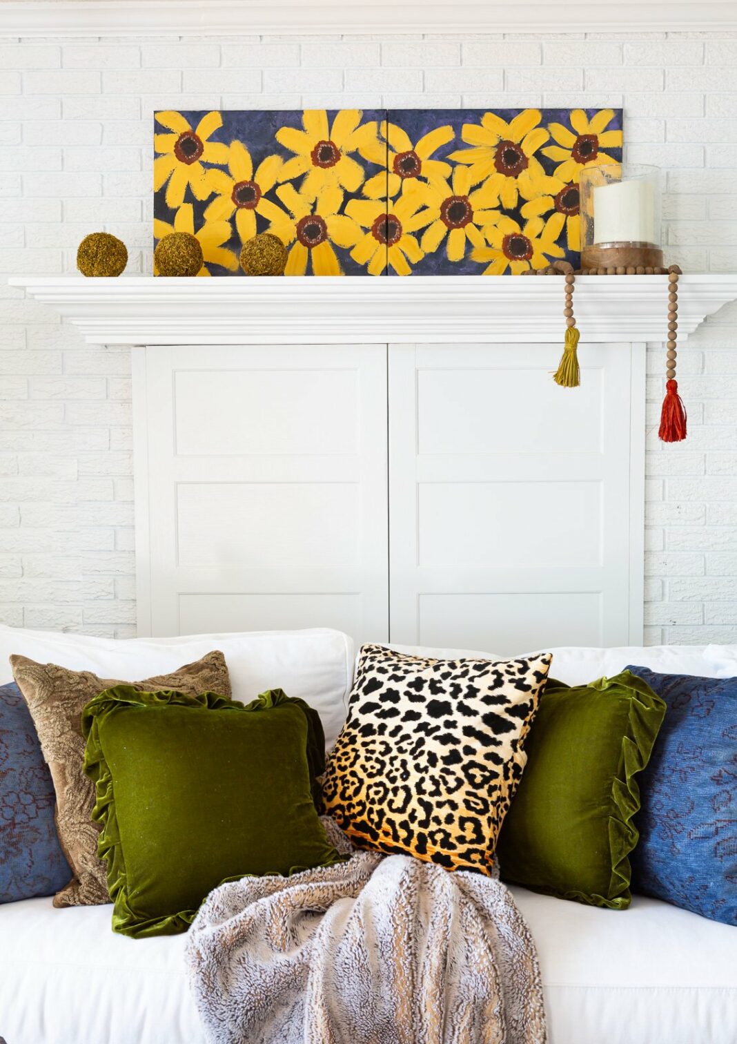 simple fall decor on a fireplace mantel in a white room with blue, green and burnt yellow accents.