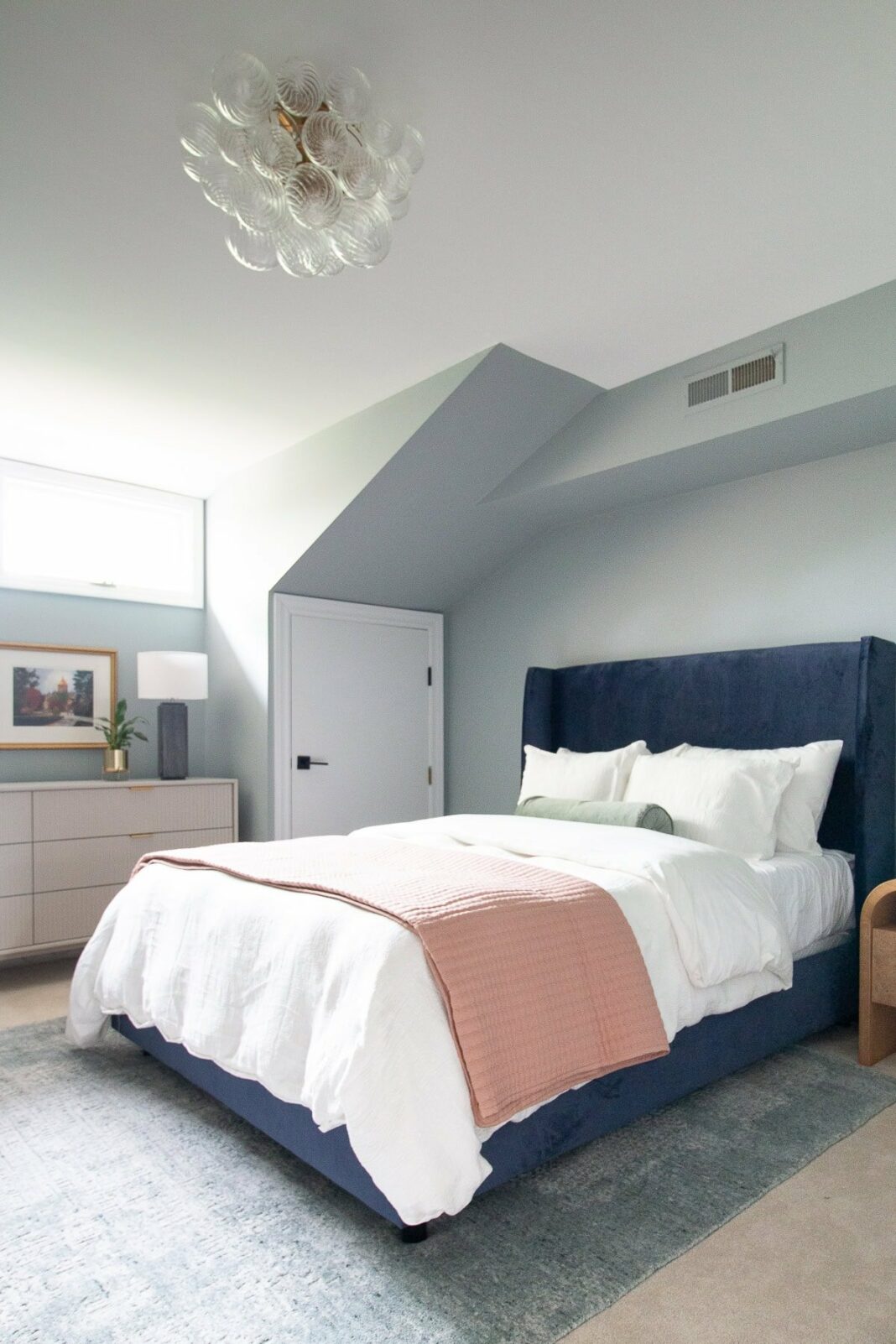 A grey and blue bedroom with a navy bed frame